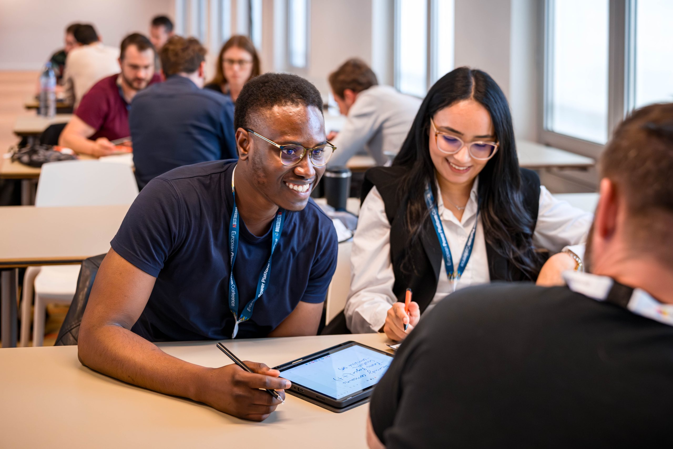 man smiling while working at a desk in a group session at a conference