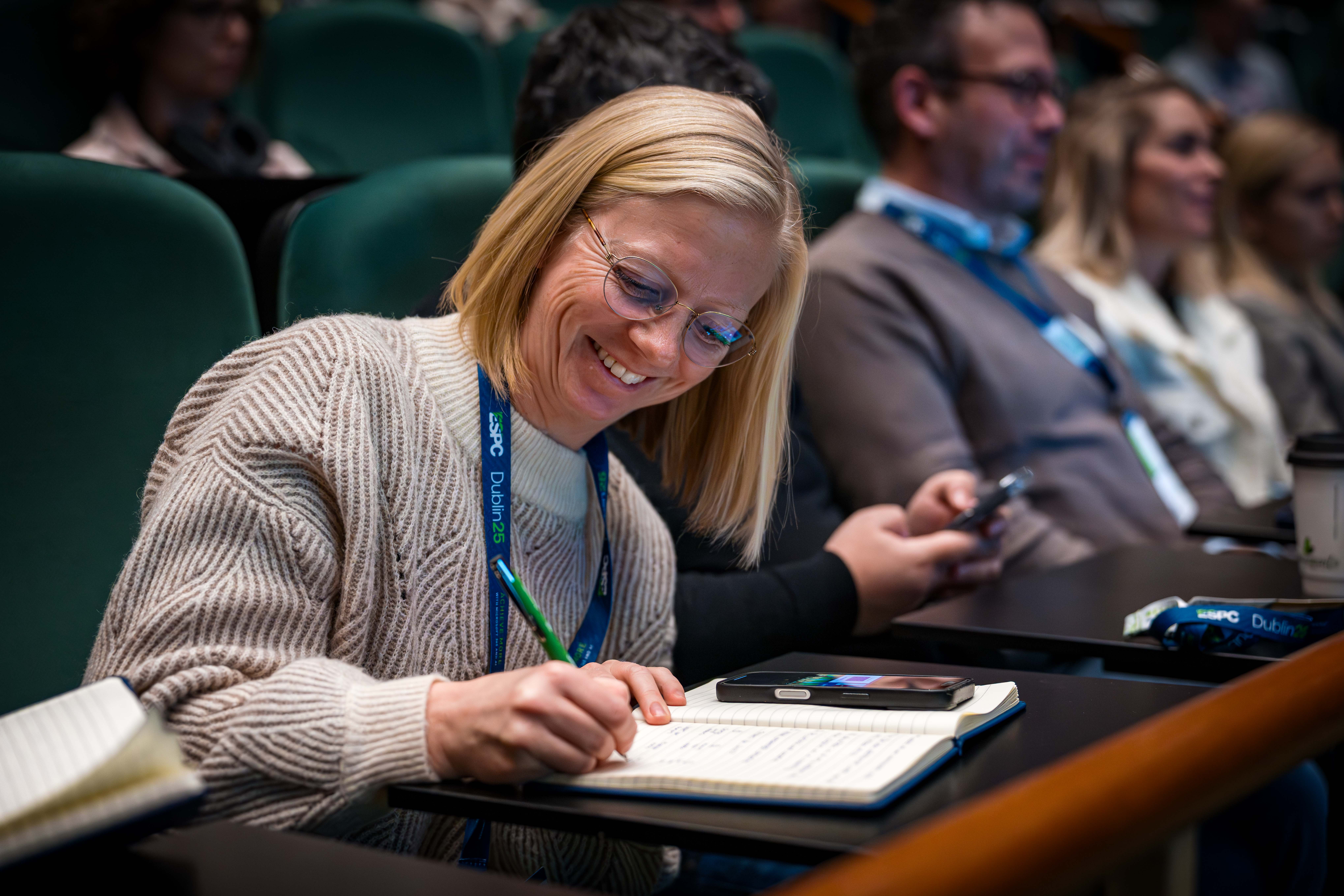 Woman happy and smiling taking notes in a session