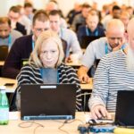 woman working at a laptop in a busy conference room