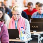 Woman sitting at a desk and working on a laptop during a conference tutorial