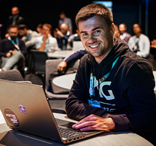 Man working at a laptop smiling at the camera