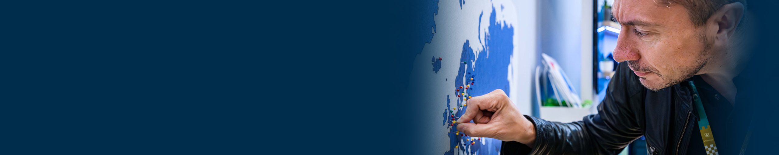 hero banner, man with map putting pin in different countries