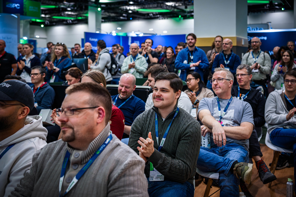 A large crowd of people applauding while sitting down in the conference EXPO hall