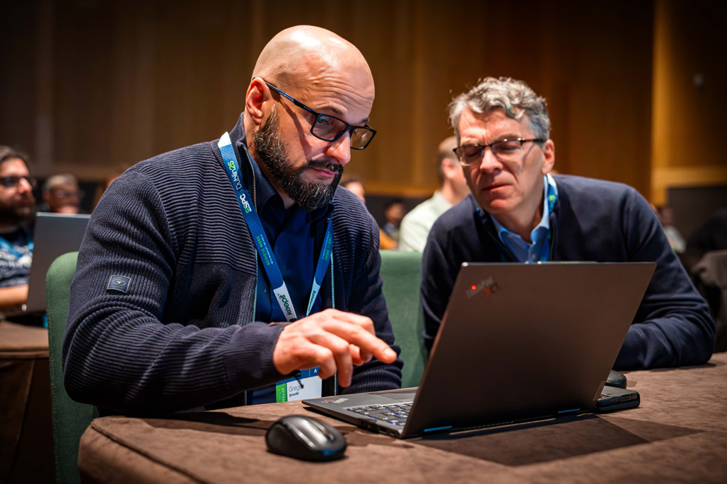 two people sitting in a conference tutroial looking at a laptop screen