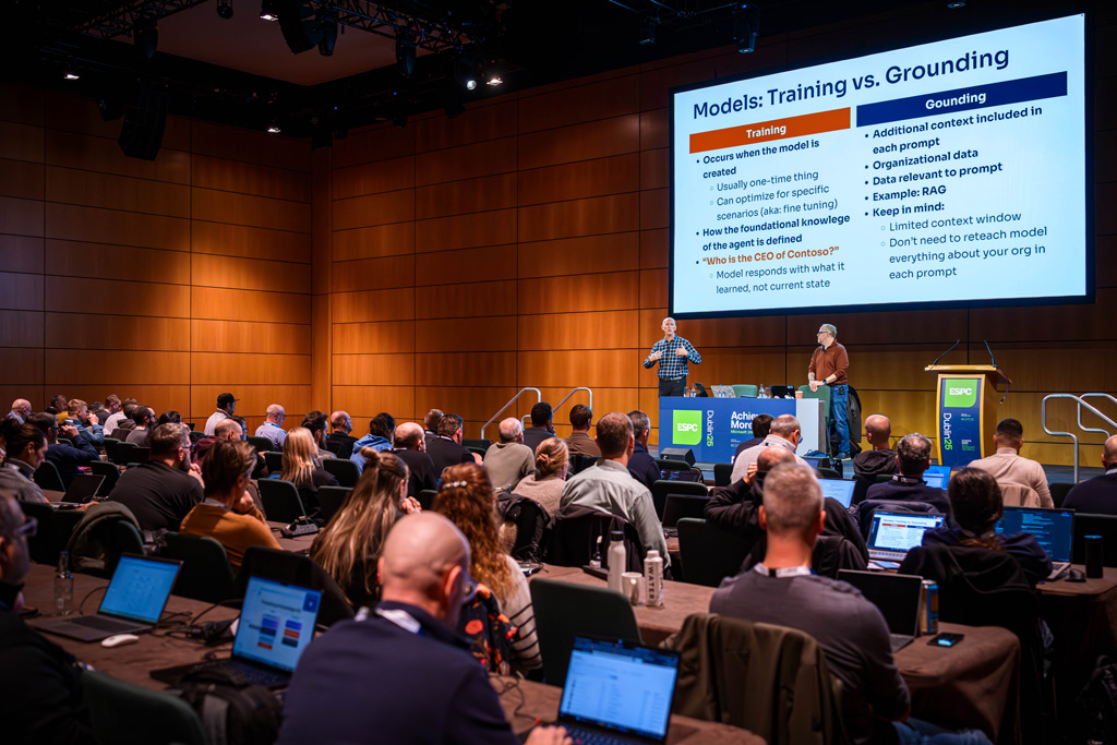 Wideshot of a two speakers on a stage addressing the attendees in a conference tutorial