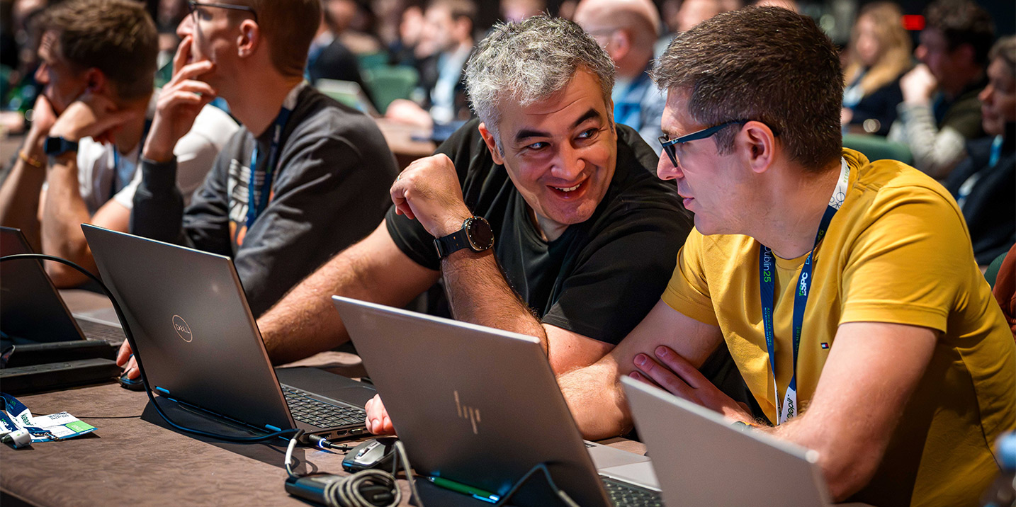 two people talk closely to each other while sitting at their laptops during a tutorial