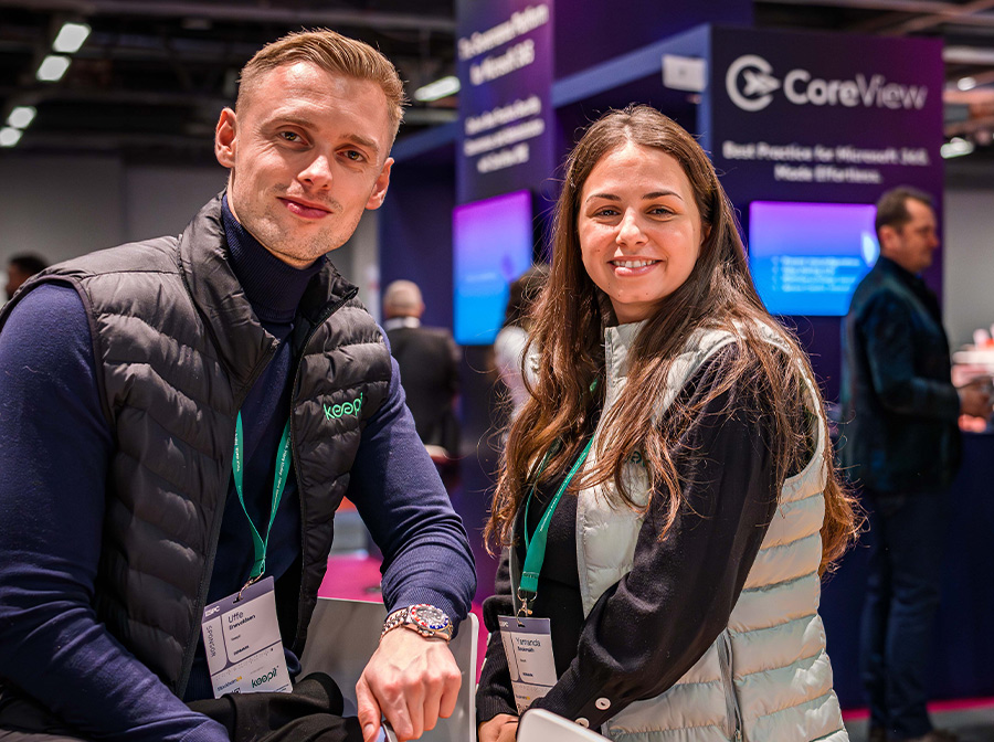 Two members of a sponsorship team smile for the camera while working in the EXPO hall
