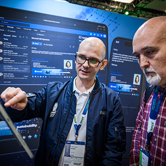two people look at a computer screen during a demo at a sponsor booth in the expo hall