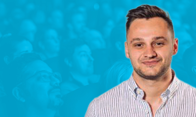 ESPC sponsor Will Garrow smiles for the camera over a background of a sitting audience