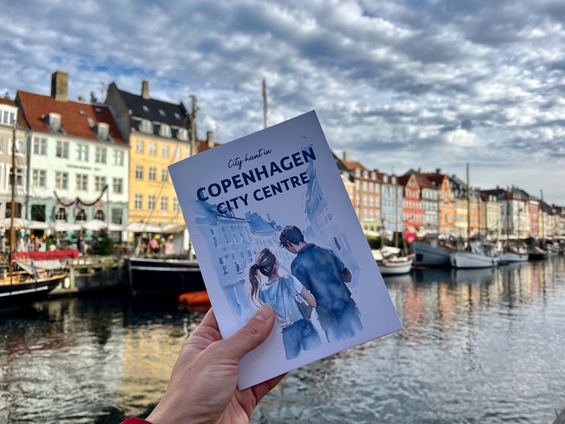 City Hunt Tour Book infront of a river and colourful buildings in Copenhagen
